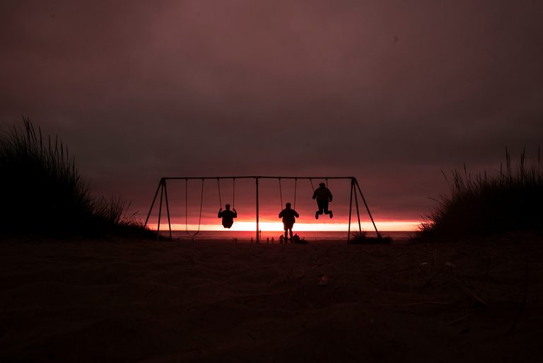Three children swinging in the sunset